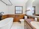 Modern bathroom features white tiled floor, half wood-paneled walls, a tub, and dark fixtures at 1737 Prince Philip St, Clearwater, FL 33755