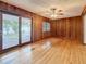 Den with wooden paneling, hardwood floors, ceiling fan, and glass paneled doors that lead outside at 1737 Prince Philip St, Clearwater, FL 33755