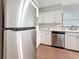 A view of the white cabinets, stainless steel dishwasher and stainless steel refrigerator in the kitchen at 1737 Prince Philip St, Clearwater, FL 33755