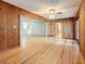 A view into the living room from the den, showcasing wooden paneling, ceiling fan and hardwood floors at 1737 Prince Philip St, Clearwater, FL 33755