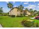 A tan two-story building featuring palm trees, landscaping, and lawn at 1801 E Lake Rd # 20 G, Palm Harbor, FL 34685