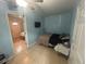 A bedroom painted light blue features a small bed, ceiling fan, tile flooring, and access to an adjacent room at 18133 Us Highway 41, Spring Hill, FL 34610