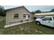 Tan, single-story home featuring a cozy front yard and a covered carport with a white truck at 18133 Us Highway 41, Spring Hill, FL 34610