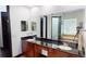 Spacious bathroom featuring double sinks, wood cabinetry, a large mirror, and a view of the soaking tub at 20023 Pergola Bend Ln, Tampa, FL 33647