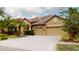 The house features an attached three-car garage with decorative windows, side coach lights, and manicured shrubbery at 20023 Pergola Bend Ln, Tampa, FL 33647