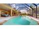 A captivating screened-in pool with a spa, surrounded by lush greenery and a spacious patio at 20023 Pergola Bend Ln, Tampa, FL 33647