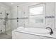 Bright bathroom featuring a soaking tub and glass enclosed shower with marble tile at 27209 Firebush Dr, Wesley Chapel, FL 33544