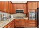Well-lit kitchen featuring granite countertops, wooden cabinets, and modern stainless steel appliances at 27209 Firebush Dr, Wesley Chapel, FL 33544