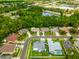 Aerial view features a neighborhood with tree coverage and a pond behind commercial buildings and homes at 28390 Openfield Loop, Wesley Chapel, FL 33543