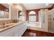 Well-lit bathroom with double sinks, a soaking tub, glass block window, and a separate shower, showcasing functionality at 28390 Openfield Loop, Wesley Chapel, FL 33543