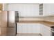 A closer view of the kitchen with white cabinets, glass cabinet doors, and stainless refrigerator at 2876 Bayshore Trails Dr, Tampa, FL 33611