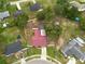 An elevated view highlights a house with a red roof, showcasing neighborhood homes, mature trees, and greenery at 3509 King George Ln, Seffner, FL 33584