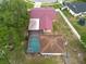 Aerial shot highlighting a property featuring a swimming pool and a unique red roof, surrounded by lush greenery at 3509 King George Ln, Seffner, FL 33584