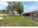 Expansive backyard with a well-maintained lawn, large trees, a basketball hoop, and a screened-in pool at 3509 King George Ln, Seffner, FL 33584