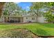 Large backyard with a covered patio, manicured lawn, and mature trees at 4309 W Empedrado St, Tampa, FL 33629