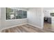 Room view with white wood walls, light wood flooring, a large window, and access to the kitchen at 5048 5Th S Ave, St Petersburg, FL 33707