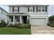 Two-story home with gray exterior, dark shutters, manicured lawn, covered front porch and attached two-car garage at 5214 Granite Dust Pl, Palmetto, FL 34221