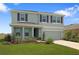 Two-story home with gray exterior paint, dark shutters, manicured lawn, and covered front porch and an attached two-car garage at 5214 Granite Dust Pl, Palmetto, FL 34221