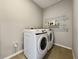 Laundry room featuring modern white washer and dryer set, tile flooring, and wire rack shelving at 5214 Granite Dust Pl, Palmetto, FL 34221