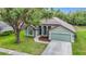 Home exterior featuring a well-kept lawn, mature trees, and a tidy two-car garage at 5809 Silas Creek Ln, Wesley Chapel, FL 33545