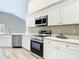 Bright kitchen featuring stainless steel appliances, white cabinetry, and stone countertops for a modern and stylish design at 5809 Silas Creek Ln, Wesley Chapel, FL 33545