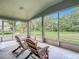 Screened-in porch showcasing wooden chairs and picturesque views of the expansive backyard at 5809 Silas Creek Ln, Wesley Chapel, FL 33545