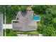Aerial view showcases a screened pool surrounded by lush green landscaping and a home with a textured roof at 6011 Pratt St, Tampa, FL 33647