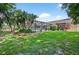 Sprawling backyard features lush lawn, tropical foliage, and a screened-in pool perfect for outdoor living at 6011 Pratt St, Tampa, FL 33647
