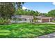 Single story home showcasing a lush lawn, mature trees, and neutral exterior at 6011 Pratt St, Tampa, FL 33647