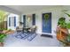 Inviting front porch with seating area and a blue patterned rug leading to the blue front door at 6412 S Richard Ave, Tampa, FL 33616