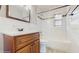 Bathroom with wood vanity, white tiled walls, and tub with mosaic tile accent at 6901 10Th N St, St Petersburg, FL 33702