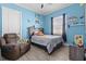 Comfortable bedroom with blue walls, wood-look floors, ceiling fan, and chair, creating a cozy and inviting space at 716 Laurel Ave, Venice, FL 34285