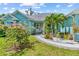 Charming blue single-story home featuring a paved walkway and lush landscaping with palm trees at 716 Laurel Ave, Venice, FL 34285
