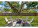 Well-manicured backyard featuring a large tree, fire pit, and Adirondack chairs at 7210 S Sparkman St, Tampa, FL 33616
