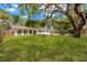 Expansive backyard featuring a lush lawn, a fire pit area, a pool, and a mature tree providing ample shade at 7210 S Sparkman St, Tampa, FL 33616
