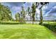 Expansive backyard features lush green grass and mature trees along the lake, offering a peaceful outdoor setting at 9827 Sorbonne Loop, Seffner, FL 33584