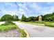 Well-maintained community entrance with lush landscaping, signage, and paved road at 9827 Sorbonne Loop, Seffner, FL 33584