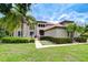 Stately home featuring a meticulously manicured front lawn, terracotta tile roof, and mature palm trees enhancing curb appeal at 9827 Sorbonne Loop, Seffner, FL 33584