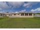 View of the backyard featuring a concrete block fence, grassy area, and white building at 10005 41St N St, Pinellas Park, FL 33782