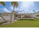 Attractive single-story home featuring a white exterior, palm trees, and manicured lawn with flower beds, offering a sunny appeal at 10005 41St N St, Pinellas Park, FL 33782