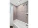 Modern bathroom features gray tiled walls, a bathtub with shower, and a clean, bright aesthetic at 10339 111Th St, Largo, FL 33778