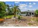 View of backyard with tropical landscaping, lawn, patio seating, and exterior of the home at 11775 84Th Ave, Seminole, FL 33772