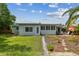 Exterior view of a well-maintained home featuring a lush yard, patio seating, and tropical landscaping at 11775 84Th Ave, Seminole, FL 33772