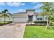 Charming one-story home featuring a brick driveway and a lush, landscaped front yard at 11785 Little River Way, Parrish, FL 34219