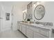 The double sink vanity is accented with granite countertops, oval mirrors, and modern lighting at 1191 Darlington Oak Ne Dr, St Petersburg, FL 33703
