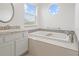 A bright bathroom features a soaking tub, white cabinets, and a round window at 1191 Darlington Oak Ne Dr, St Petersburg, FL 33703