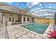 A backyard pool is encased by a screened-in enclosure and is surrounded by paved patio and home features at 1191 Darlington Oak Ne Dr, St Petersburg, FL 33703