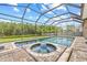 Screened pool and hot tub with lush greenery, brick pavers, and blue sky in the background at 1191 Darlington Oak Ne Dr, St Petersburg, FL 33703