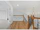 A staircase landing has hardwood floors and a decorative wood and black iron railing with white walls at 1191 Darlington Oak Ne Dr, St Petersburg, FL 33703