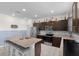 Well-lit kitchen features stainless appliances, granite countertops, oversized island and dark cabinets at 12481 Aston Dr, Hudson, FL 34669